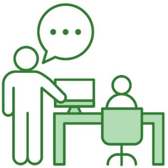 A person standing next to someone at a desk and supporting them to do their work.