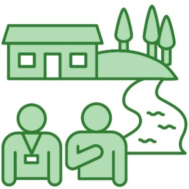 A person wearing a lanyard supporting someone. There is a mountain, trees, a river and a house behind them.