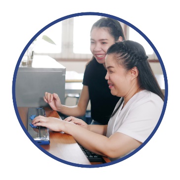 A person supporting someone to use a computer.